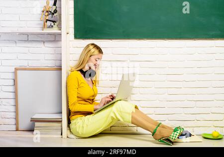 E-learning. Lesson and education in high school. Smiling student girl sitting on floor preparing for test or exam at home using laptop. Talk, internet Stock Photo