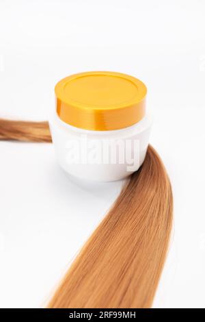 Mockup Blank bottle of Shampoo, Hair Mask or Conditioner with Golden Cap Wrapped In Shiny healthy Brown hair Strand on White Background. Natural Stock Photo