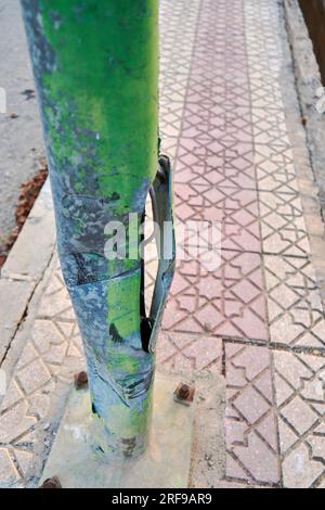 ruined part of a metallic pole on the sidewalk Stock Photo