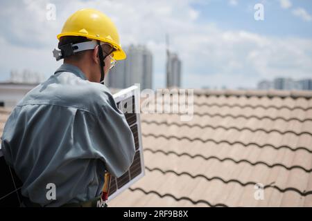 Contractor carrying solar panel, when walking on roof Stock Photo