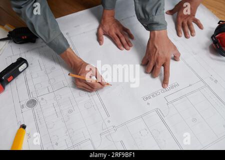 Hands of builders checking construction plan before starting work, view from above Stock Photo