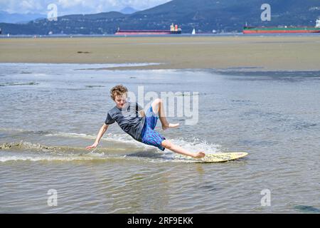 Beach fun, Boy skim boarding  at low tide. Stock Photo