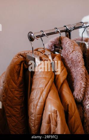 Beige brown women's clothes hanging on a hanger in a row. Autumn winter fashion collection set Stock Photo