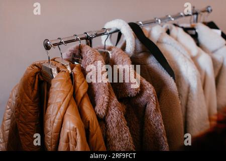 Beige brown women's clothes hanging on a hanger in a row. Autumn winter fashion collection set Stock Photo