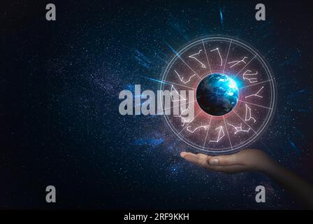 Woman holding illustration of Earth with zodiac wheel around it in open space, closeup Stock Photo