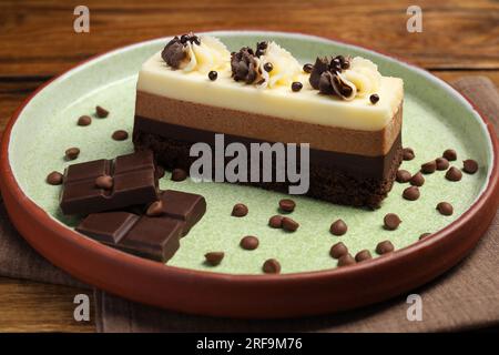 Tasty mousse cake and chocolate on plate, closeup Stock Photo