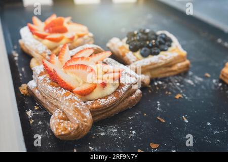 Danish strawberry and blueberry on a black tray sold in pastry shop cafe bakery. Stock Photo