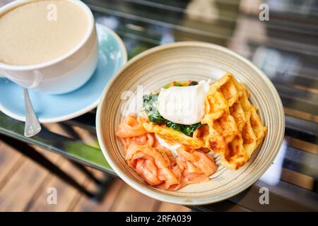 Potato waffles, Poached egg, avocado cream with salmon and egg . Healthy breakfast, protein. Restaurant dish.  Stock Photo