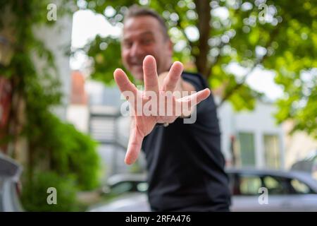 Man reaching out with his hand to the camera with the focus on the hand Stock Photo