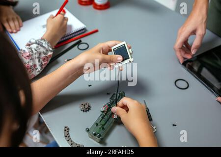 Unrecognizable female student connecting solar panel to electrical circuit in a robotics class. Elementary technological education concept. Stock Photo