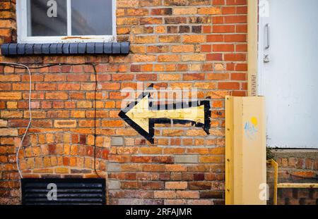 Arrow painted on building pointing to the left Stock Photo