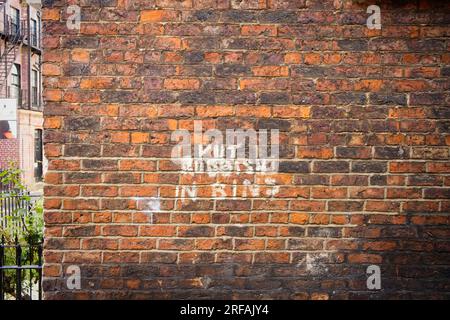 Put rubbish in bins painted on a brick wall Stock Photo