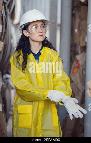 Long-haired inspector putting on gloves helps sort waste Stock Photo