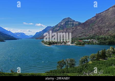 view across turquoise-colored waterton lakes to prince of wales hotel  in waterton, alberta, canada, to  peaks of glacier national park, montana Stock Photo