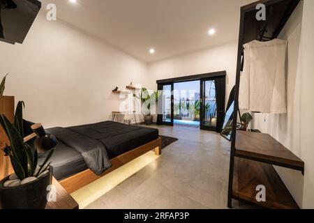 Luxury white bedroom with modern wooden bed in loft style interior design room. Stock Photo
