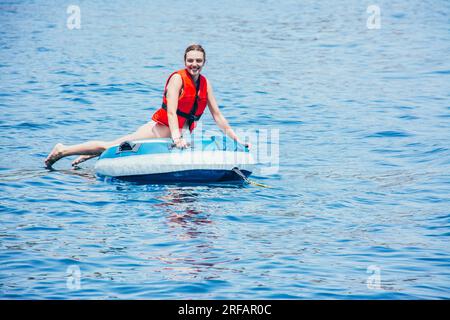 Smiling young woman enjoying in the sea on an inflatable donut, looking at the camera Stock Photo