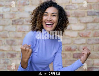 Cheering mexican woman with curly hair in urban style Stock Photo