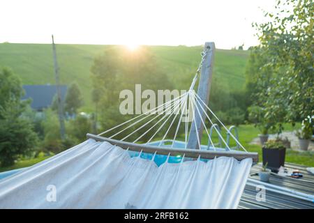 Hammock hangs on wooden terrace with table at a vineyard. Concept of paradise corner in industrial district of big city. Stock Photo