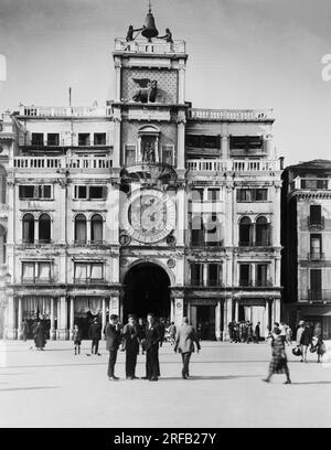 Venezia, ca 1860-1880 - Torre dell'Orologio, St.Mark's Square, . Inhabitants walking around the St.Mark's Clock Tower. The Clock Tower in Venice is an early Renaissance building on the north side of the Piazza San Marco, at the entrance to the Merceria. It includes a tower, which contains the clock, and lower buildings on each side. It adjoins the eastern end of the Procuratie Vecchie. Naya-Bohm Archive, 'Views' series.  Venezia, 1860-1880 circa - Torre dell'Orologio, Piazza San Marco. Abitanti camminano davanti la Torre dell'Orologio di San Marco. La Torre dell'Orologio a Venezia è un edifici Stock Photo