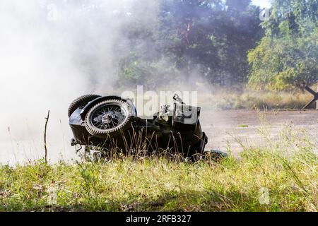 Historical reconstruction. An overturned and dirty German motorcycle between smoke and dust after a bomb explosion. Stock Photo