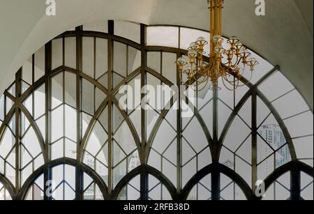 Bangkok, Thailand - Jul 28, 2023 - Chandelier (Chanderia) is hung on the roof, which is in the hall. The wall is decorated with ancient glass wall bac Stock Photo