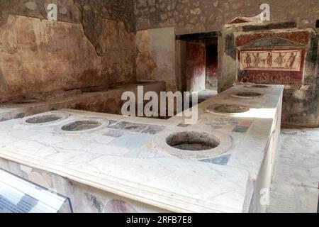 A typical roman snack bar or shop in Pompeii Archaeological Park, with terracotta Amphorae sunk under the bar counter, to hold various food and drink Stock Photo