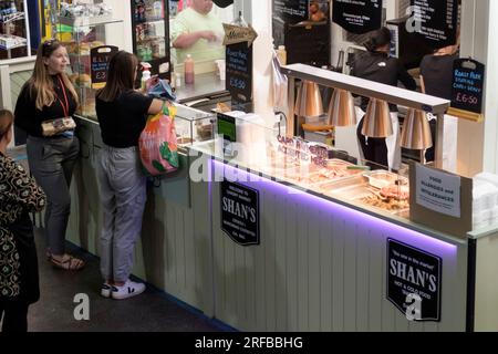 Queuing for lunch at one of the many food stalls in Cardiff Market Stock Photo