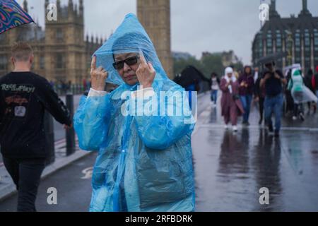 London UK. 2 August 2023   Pedestrians on Westminster bridge brave the lashing  rain and blustery conditions as the Met office issues yellow warnings  for strong winds in the UK. Credit amer ghazzal/Alamy Live News Stock Photo