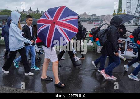 London UK. 2 August 2023   Pedestrians on Westminster bridge brave the lashing  rain and blustery conditions as the Met office issues yellow warnings  for strong winds in the UK. Credit amer ghazzal/Alamy Live News Stock Photo