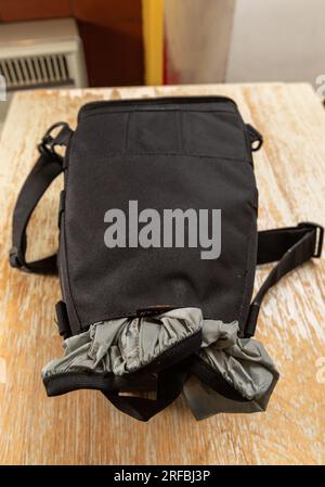 A Lowepro top loader camera bag with shoulder strap face down and with the protective rain cover partially pulled out Stock Photo