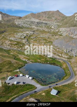 AERIAL VIEW. Picturesque Eissaupres Lake with campervans alongside the road leading to Col de la Bonette. Jausiers, Alpes-de-Haute-Provence, France. Stock Photo