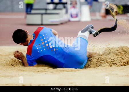 para-athlete long jump, landing in sand at athletics competition, summer sports games Stock Photo