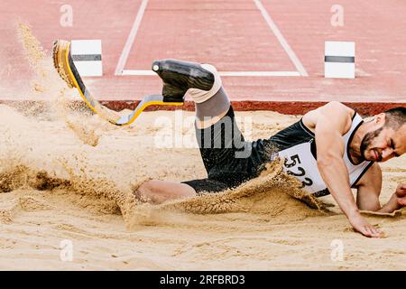 para athlete long jump, landing sand in athletics competition, summer sports games Stock Photo