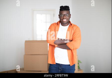 Relocation Concept. Handsome Young Black Man Posing In Room With Cardboard Boxes Stock Photo