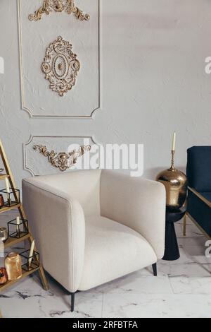 Close up shot of beige soft chair in classic style. Metal candlestick with candles in living room with elegant interior design Stock Photo