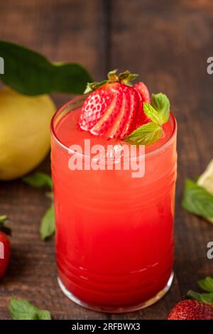 Iced strawberry lemonade in glass glass on wooden table Stock Photo