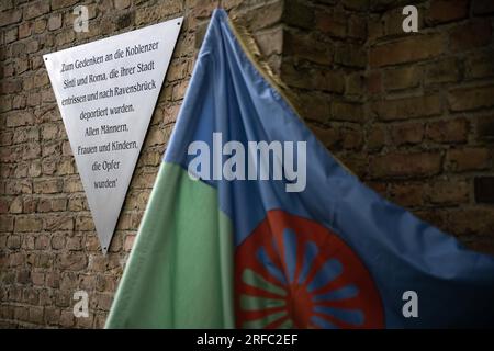 02 August 2023, Brandenburg, Fürstenberg/Havel: View of the memorial plaque, in the foreground a Sinti and Roma flag. At the Ravensbrück Memorial there is a new memorial plaque for Sinti and Roma who were deported to the concentration camp during the Nazi era. Photo: Hannes P. Albert/dpa Stock Photo