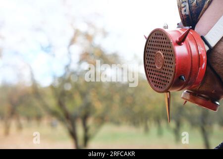 A man in a gas mask and steampunk goggles stands with his back to the camera and looks at his surroundings. Horizontal photo Stock Photo