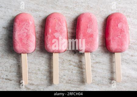 Strawberry yogurt popsicles on a beige marble background. Stock Photo