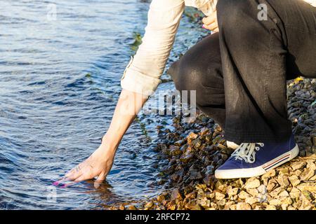 woman testing the temperature of the water with her hand. hand dipped into water. High quality photo Stock Photo