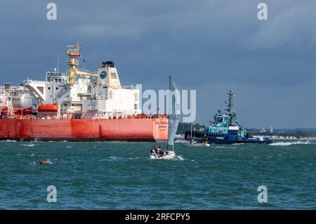 large oil tanker ship with a tug entering the oil refinery at fawley on the solent uk. tug assisting large ship in the thorn channel off of cowes IOW. Stock Photo