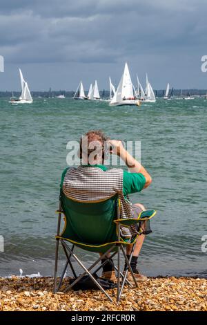 man spectating at cowes week yachting regatta on isle of wight. male sitting in camping chair watching the yachts in the cowes week sailing regatta. Stock Photo