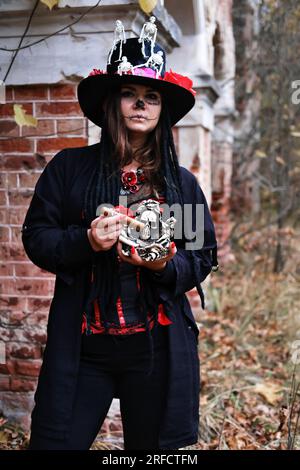 A woman in the image of Baron Saturday. The model is dressed in a corset, a cardigan and a top hat decorated with skeleton figures and poses with a ci Stock Photo