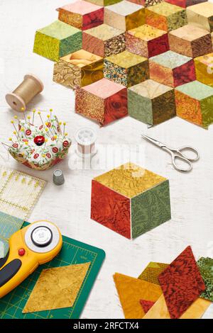 Fragment of tumbling blocks quilt, accessories for quilting on a white surface Stock Photo