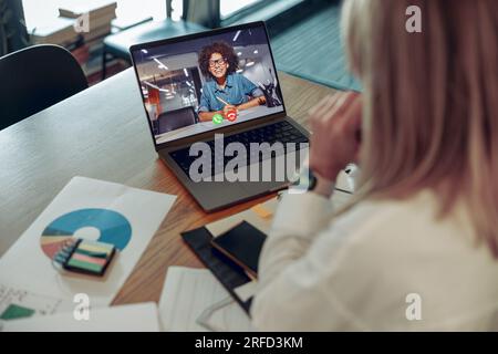 Woman analyst working with documents during video conference while sitting in modern coworking Stock Photo