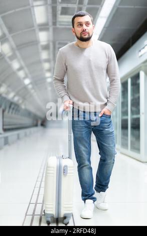Young man walking through metro station with suitcase Stock Photo