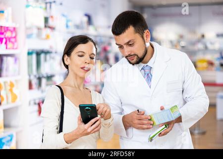 Male pharmacist consulting woman customer in drugstore Stock Photo