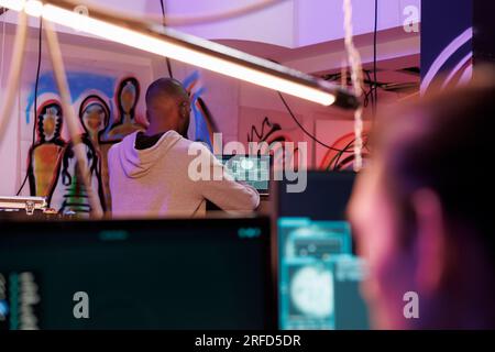 Hackers launching cyberattacks on computer network systems while working in abandoned warehouse at night. Criminals coding malicious software and planning phishing attack Stock Photo