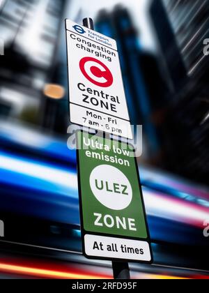 'ULEZ' ZONE SIGN SIGNAGE TFL  London area city town background Congestion/Emission charging London zone sign with 'ULEZ' ultra low emission zone sign against blurred traffic and city buildings London UK Stock Photo