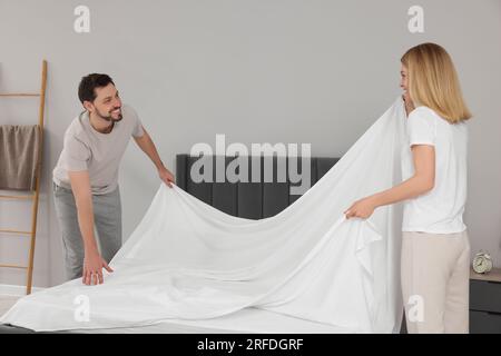 Couple changing bed linens in room. Domestic chores Stock Photo